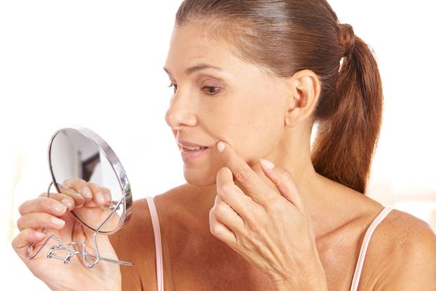 Woman checking wrinkles in mirror