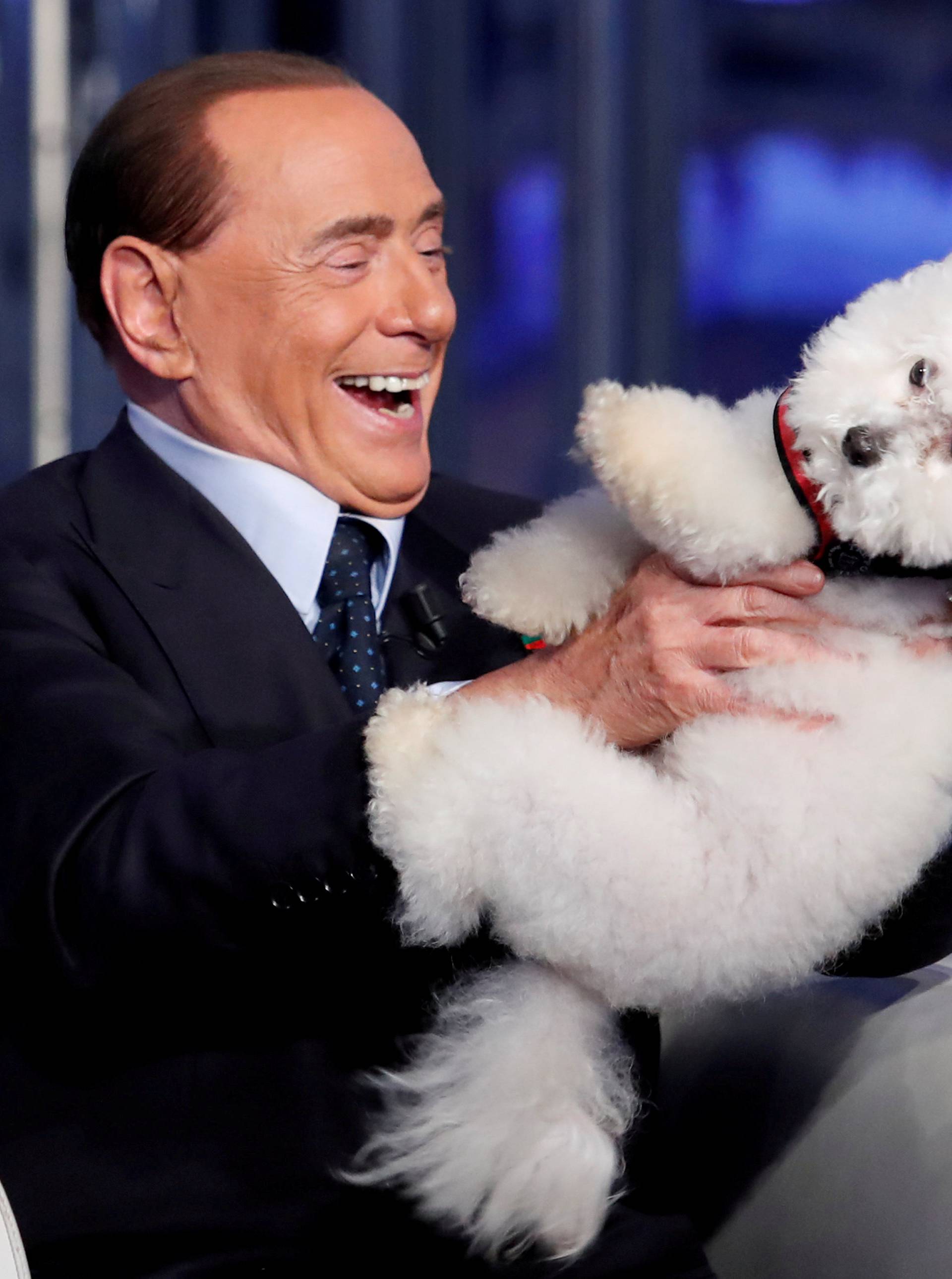 FILE PHOTO: Italy's former PM Berlusconi plays with a dog during the television talk show "Porta a Porta" in Rome