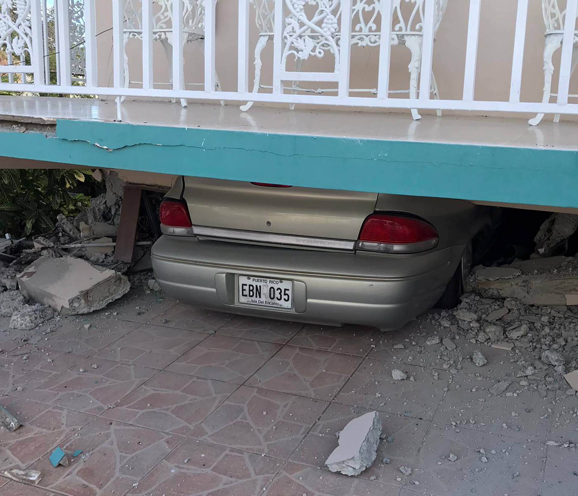 A car lies under a collapsed house after an earthquake in Guanica