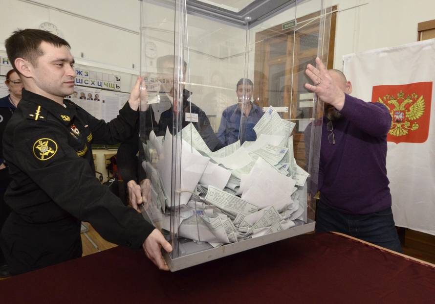 Members of a local election commission empty a ballot box before starting to count votes during the presidential election in Vladivostok