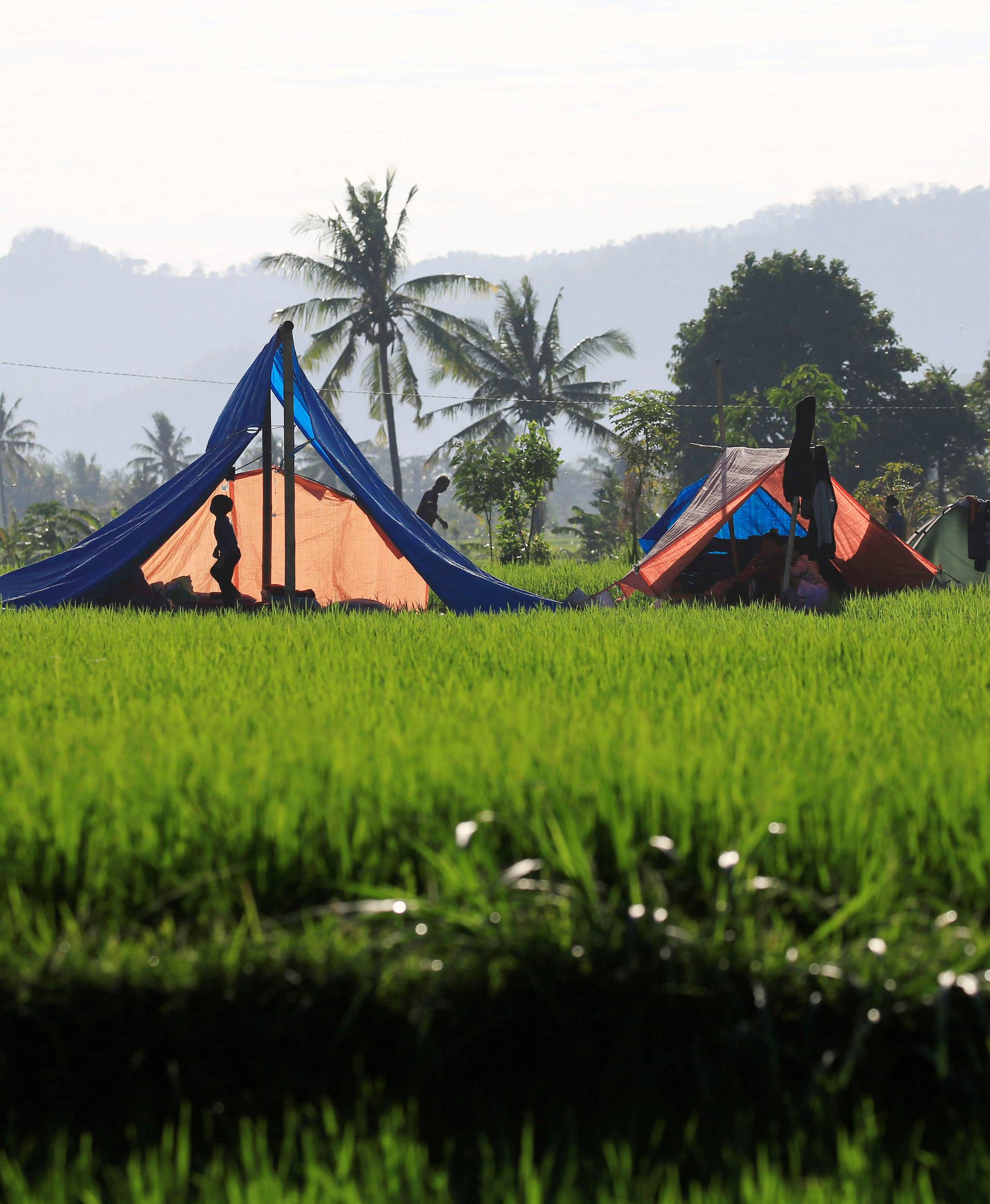 Villagers walk near their temporary shelter after an earthquake hit on Sunday in Pemenang