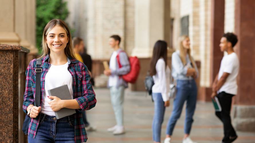 Students,Life.,Happy,Girl,Holding,Books,And,Smiling,,Standing,Against
