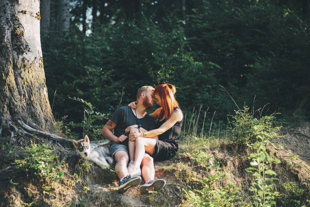 beautiful couple sitting in a forest near the tree