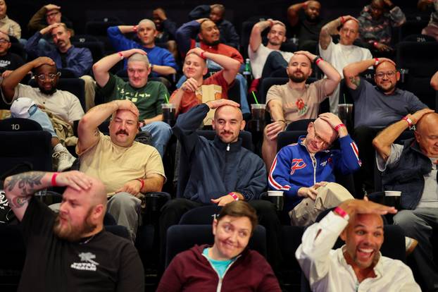 Fans with shaved heads sit in a cinema hall waiting for a free preview of Yorgos Lanthimos’s new film 'Bugonia', in California