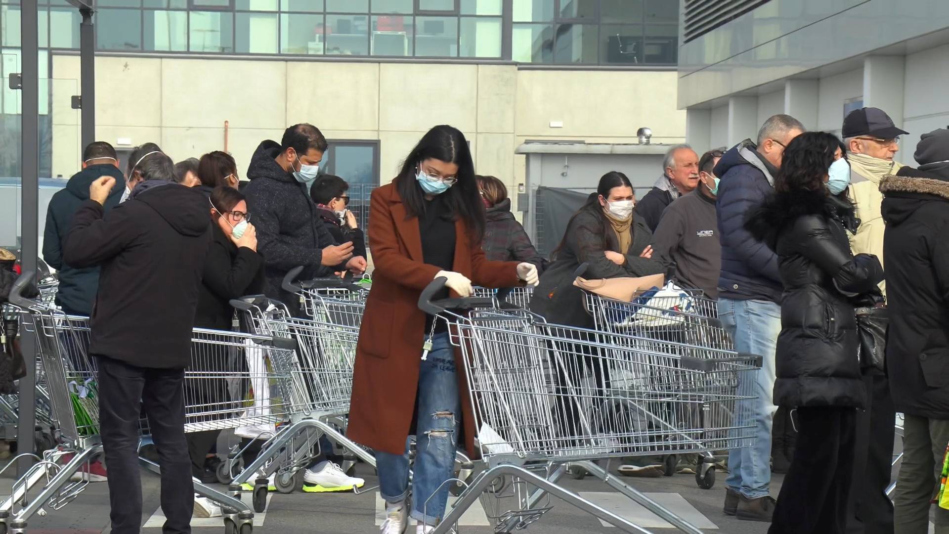 Italians wearing protective masks wait outside a closed supermarket in Casalpusterlengo