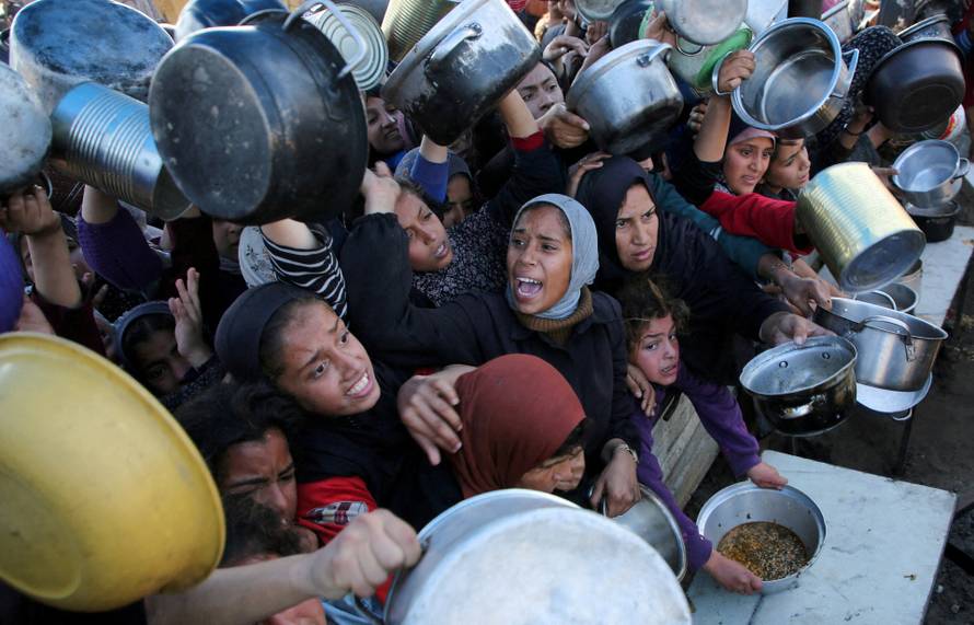 FILE PHOTO: Palestinians gather to receive food cooked by a charity kitchen, in Khan Younis