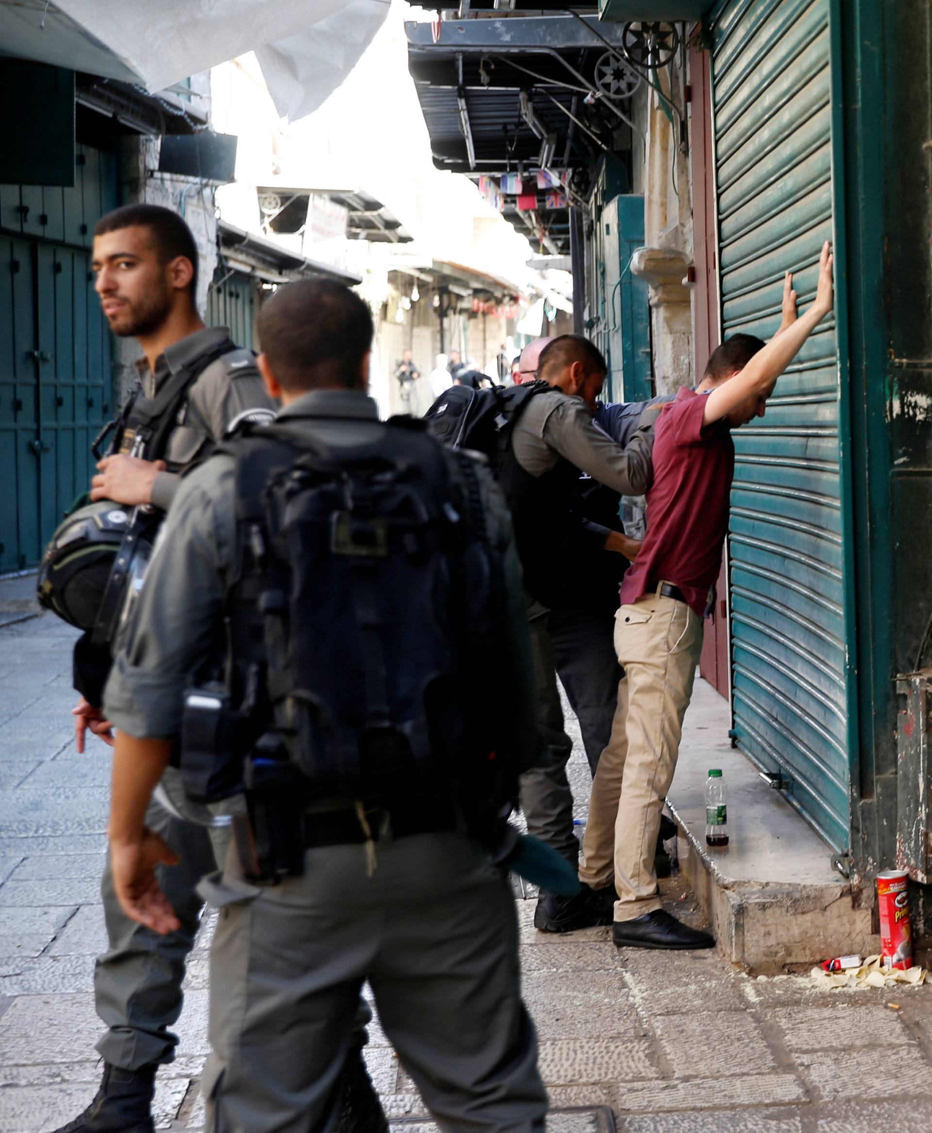 Israeli border policemen perform a body search on a Palestinian man in Jerusalem's Old City