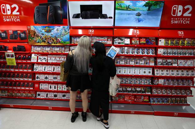 People shop at an electronics store as Nintendo starts selling the new consoles globally, in Tokyo