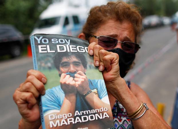 Woman holds a book "Yo soy el Diego" outside the house where Diego Maradona was staying, in Tigre