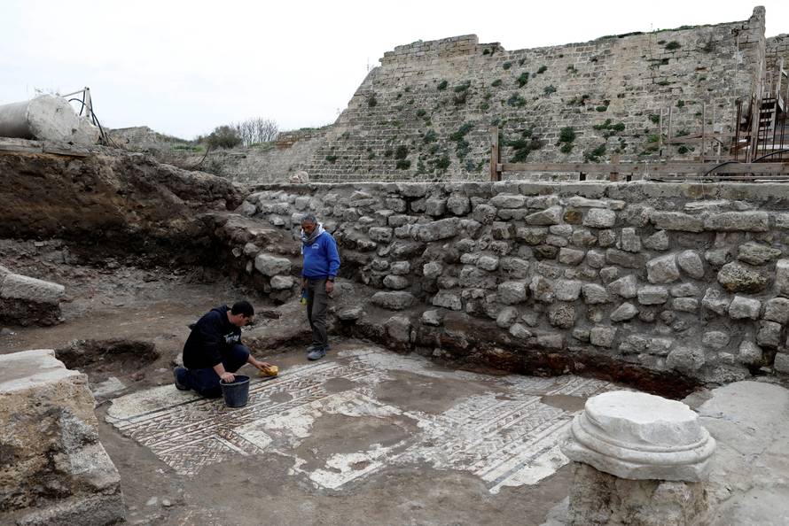 Israel Antiquities Authority workers clean a mosaic floor decorated with figures, which archaeologists say is 1,800 years old and was unearthed during an excavation in Caesarea