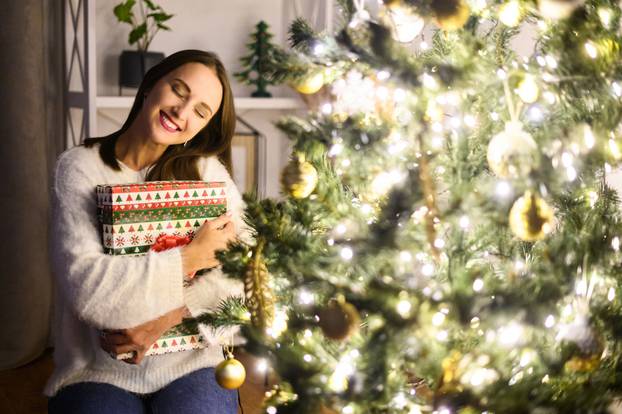 A young woman with a gift box near Christmas tree