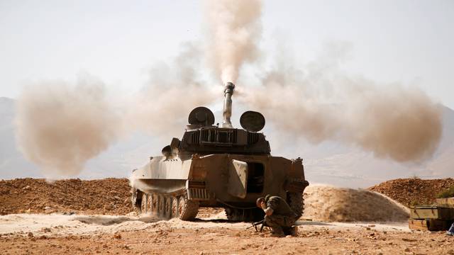 FILE PHOTO: A Hezbollah fighter reacts as he fires a weapon in Western Qalamoun