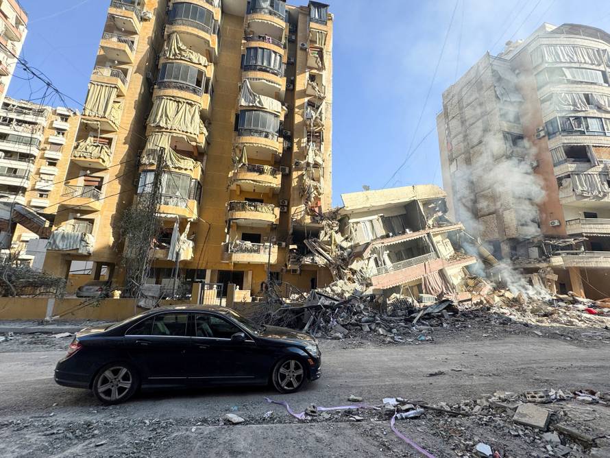 A car stops by a destroyed building after an Israeli strike on Beirut's southern suburbs