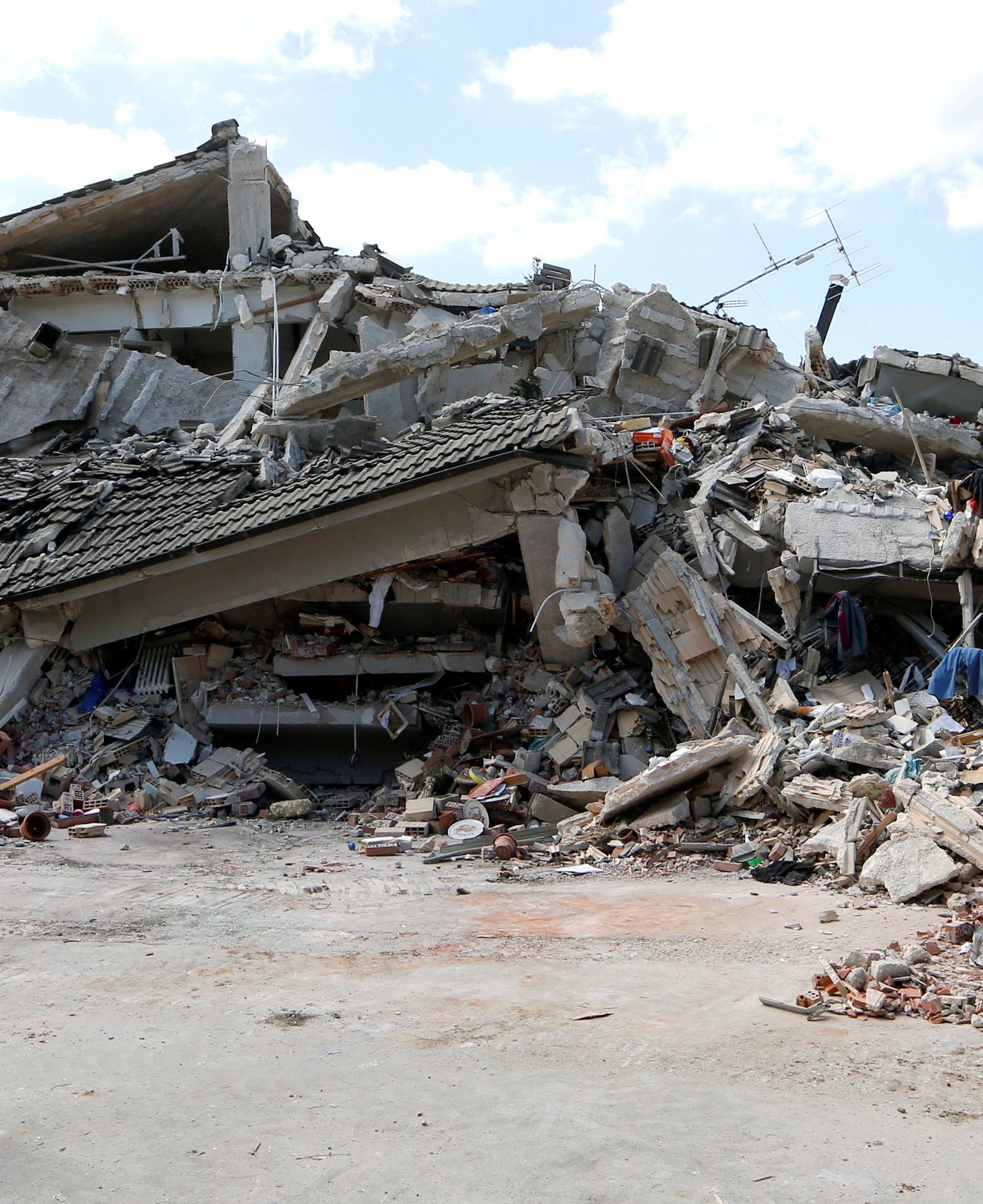 A rescuer stands in front of a collapsed building following an earthquake in Amatrice