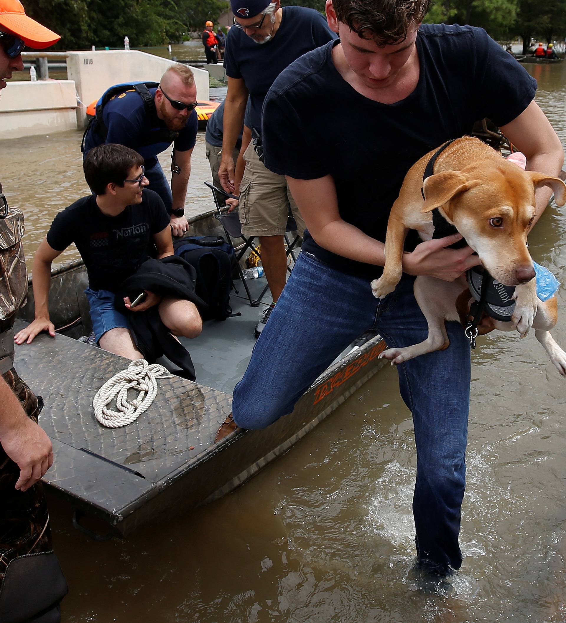 People unload belongings and dogs to cross a bridge to evacuate from the rising water of Buffalo Bayou following tropical storm Harvey in a neighborhood west of Houston