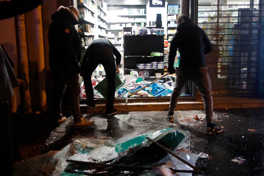 People try to clean uo a destroyed shop window on avenue Kleber after clashes with protesters wearing yellow vests, a symbol of a French drivers' protest against higher diesel taxes, in Paris