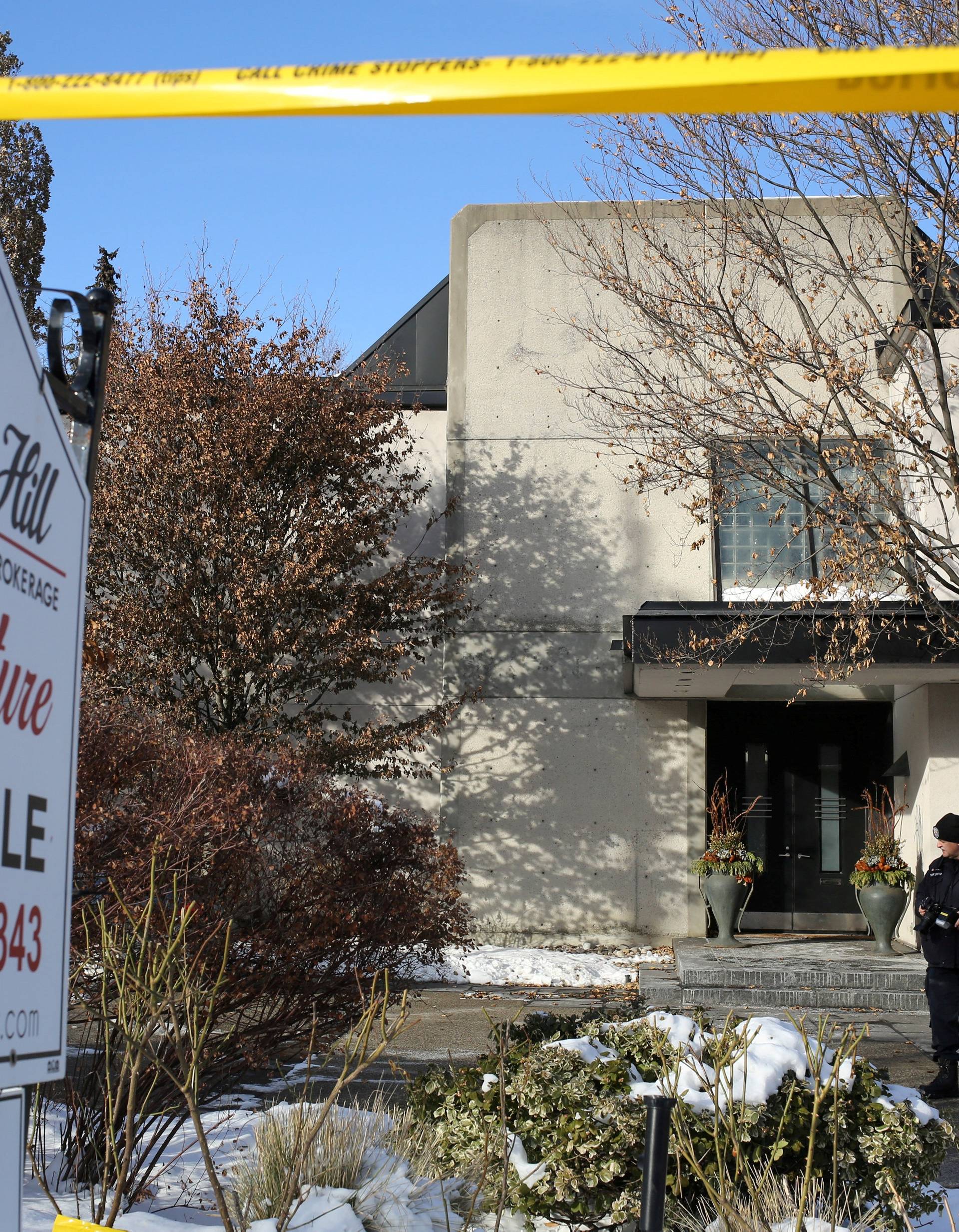 A police forensics photographer works outside the home of billionaire founder of Canadian pharmaceutical firm Apotex Inc. in Toronto