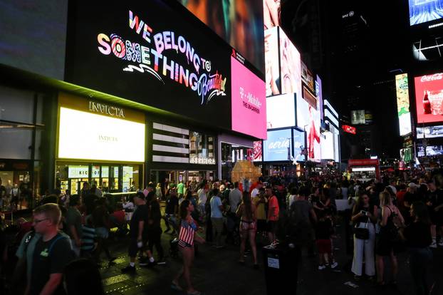 People walk near Times Square area after power was restored following a blackout that affected buildings and traffic during widespread power outages in the Manhattan borough of New York