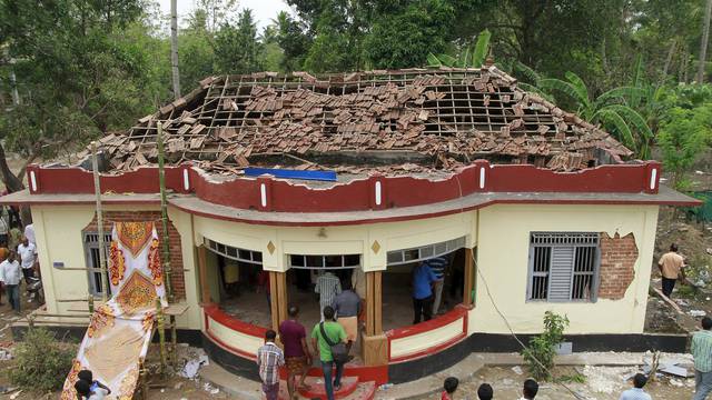 People gather around a damaged section of a temple after a fire broke out at a temple in Kollam in the southern state of Kerala