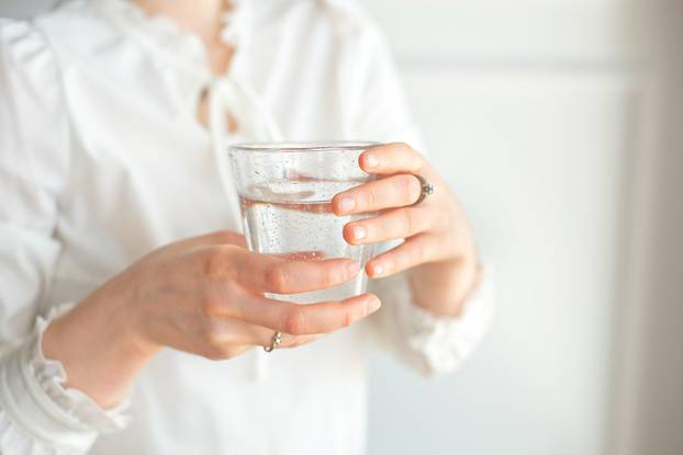 Glass of clean mineral water in woman's hands. Concept of environment protection, healthy drink