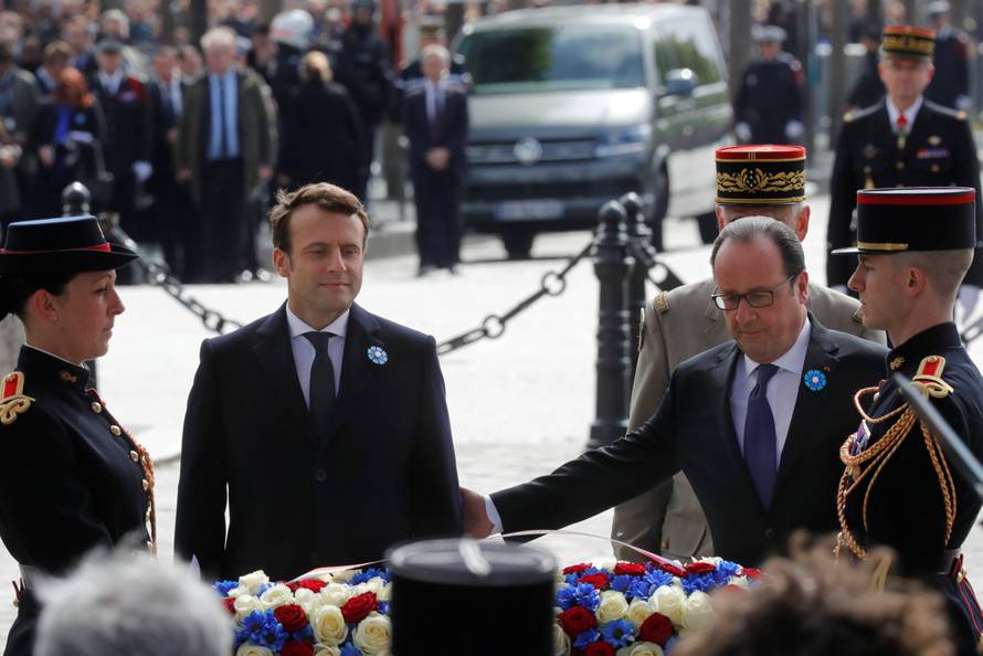 Outgoing French President Francois Hollande and President-elect Emmanuel Macron attend a ceremony to mark the end of World War II at the Tomb of the Unknown Soldier at the Arc de Triomphe in Paris