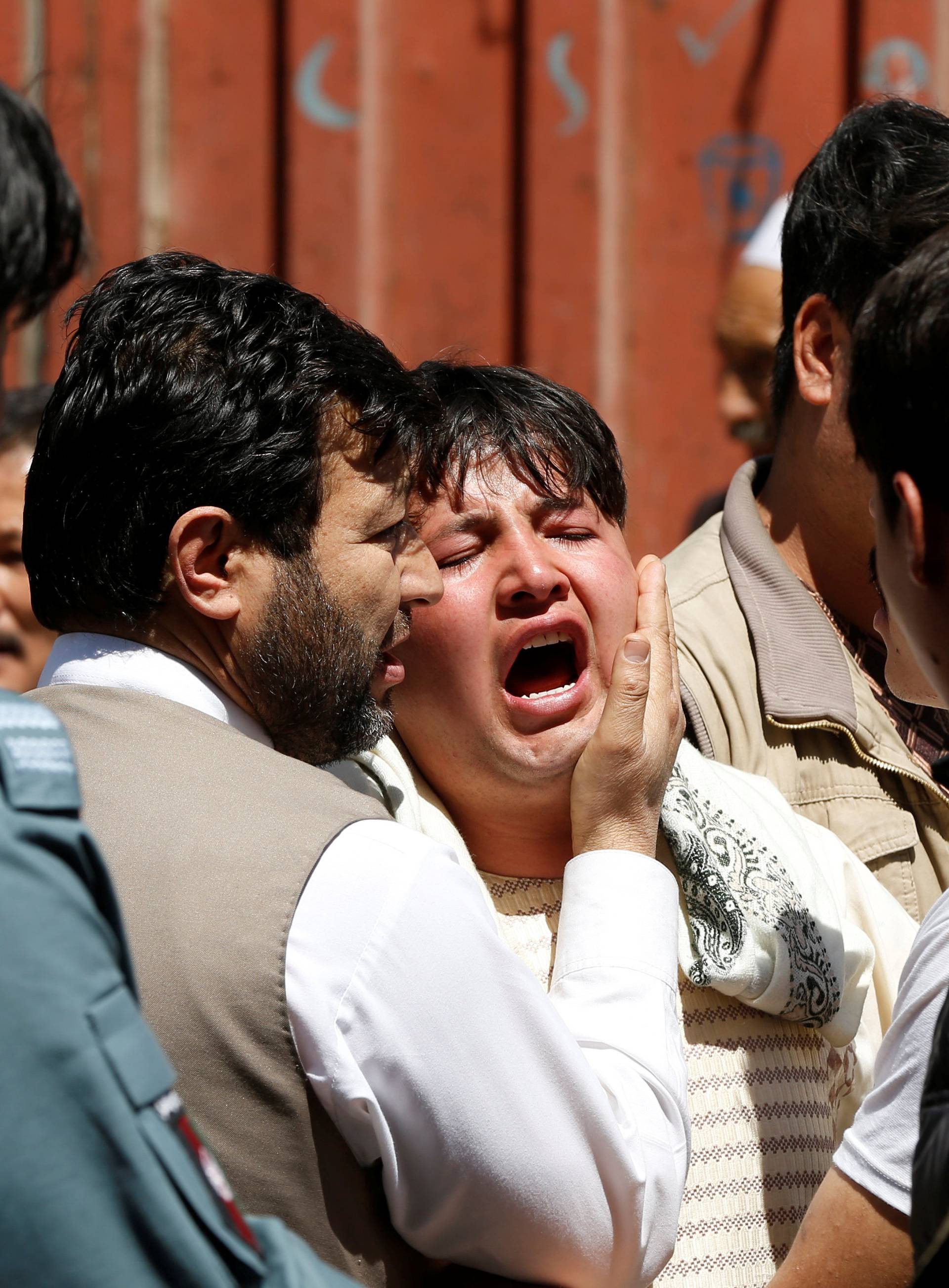 A man reacts as others comfort him at the site of a suicide attack in Kabul