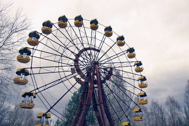 An old Ferris wheel with yellow gondolas, surrounded by trees.