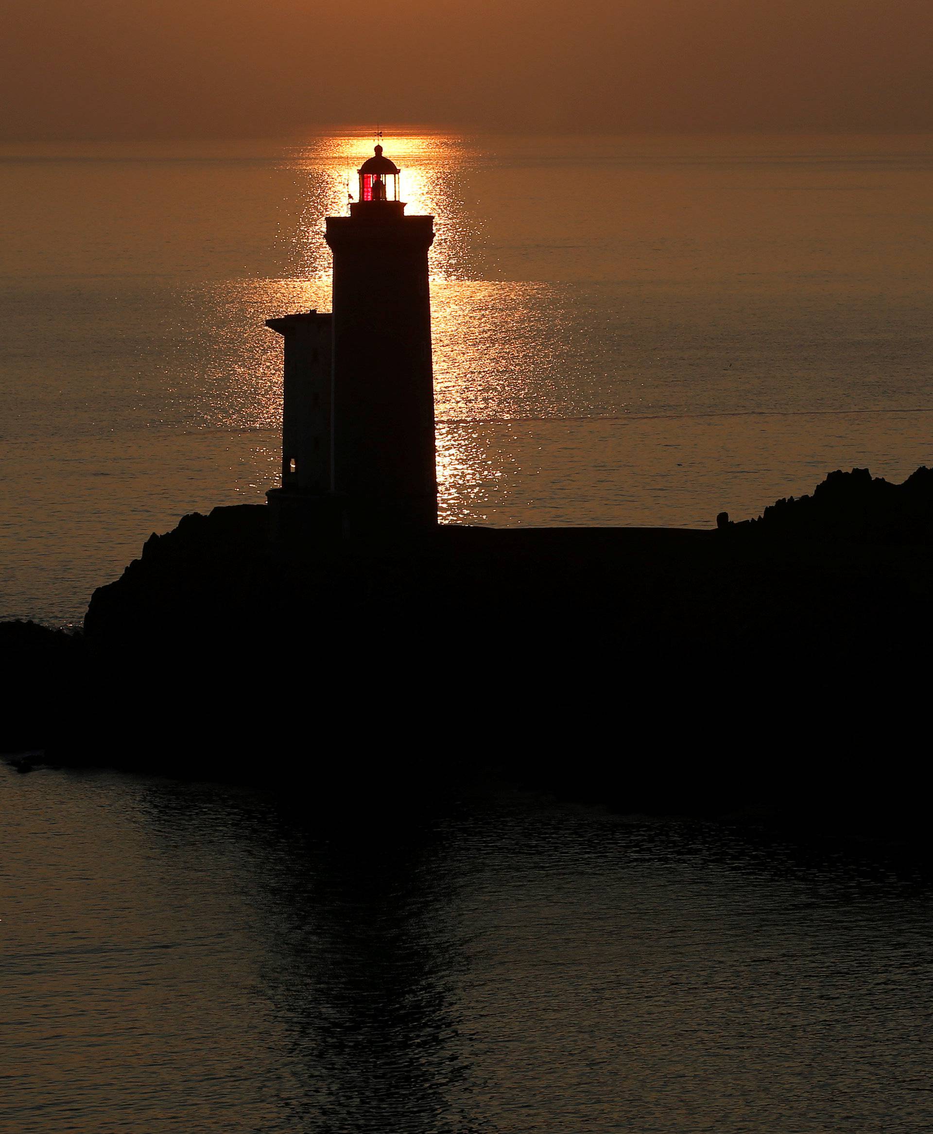 View of the Phare du Petit Minou as the sun sets over the Atlantic Ocean on a cold winter day in Plouzane
