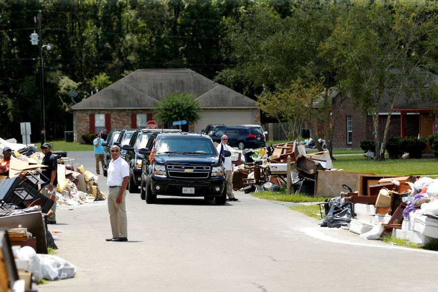U.S. President Barack Obama's motorcade is seen nearby as he tours a flood-affected neighborhood in Zachary
