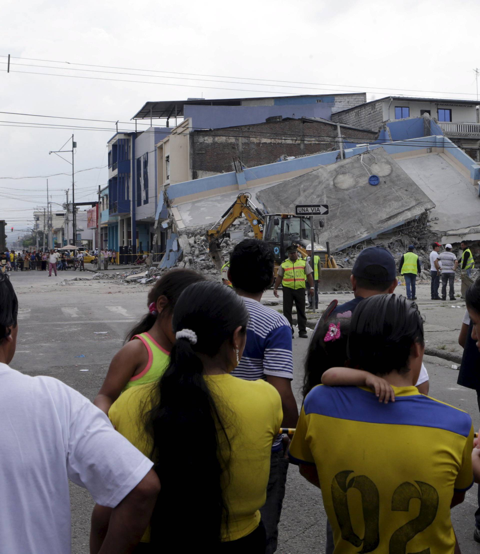 People look at a collapsed building after an earthquake struck off the Pacific coast, in Guayaquil