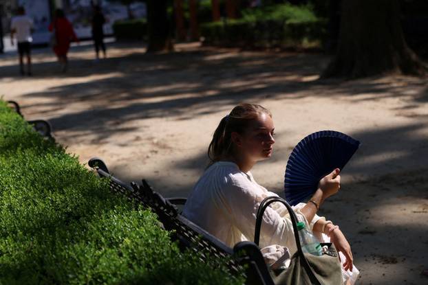 A woman uses a fan during a heatwave, in Seville