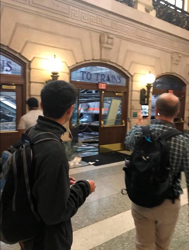 Onlookers view a New Jersey Transit train that derailed and crashed through the station in Hoboken