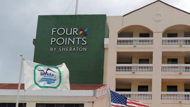 A U.S. flag and a flag of the Cuban military-run hospitality company Gaviota flutter near the logo of a  "Four Points by Sheraton" hotel in Havana