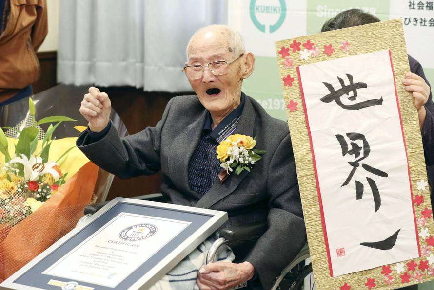112-year-old Chitetsu Watanabe poses next to the calligraphy reading 'World Number One' after being awarded as the world's oldest living male by Guinness World Records, in Joetsu, Japan