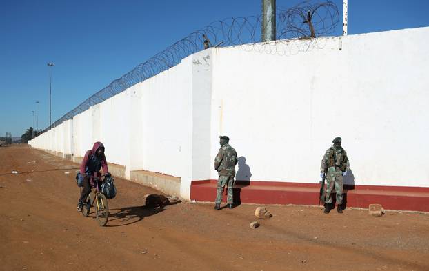 A man rides a bike past members of the South African National Defence Force (SANDF)