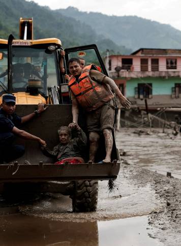 A survivor is transported to a safer place in heavy machinery following a flash flood at Trishuli, Nepal