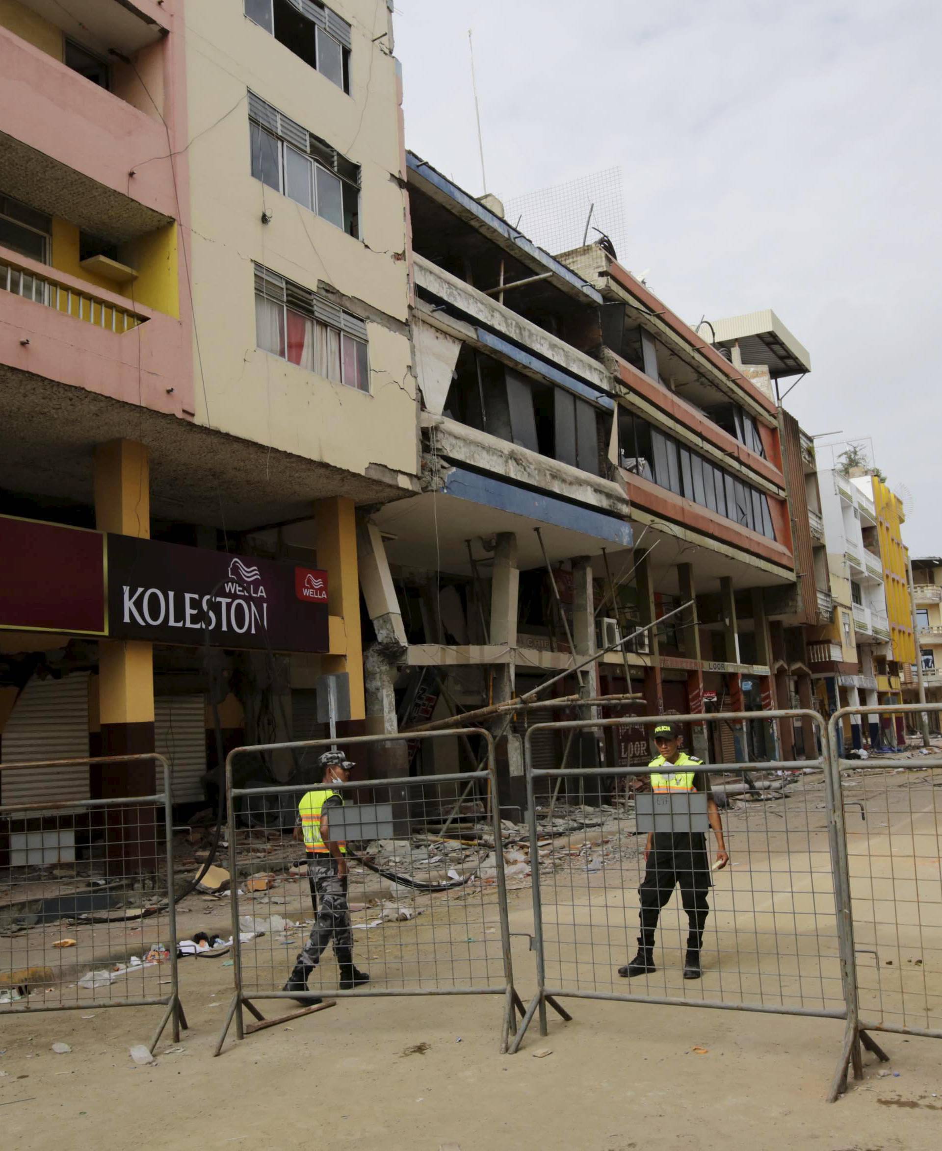 Police officers stand guard in a closed street with collapsed buildings in Portoviejo, after an earthquake struck off Ecuador's Pacific coast