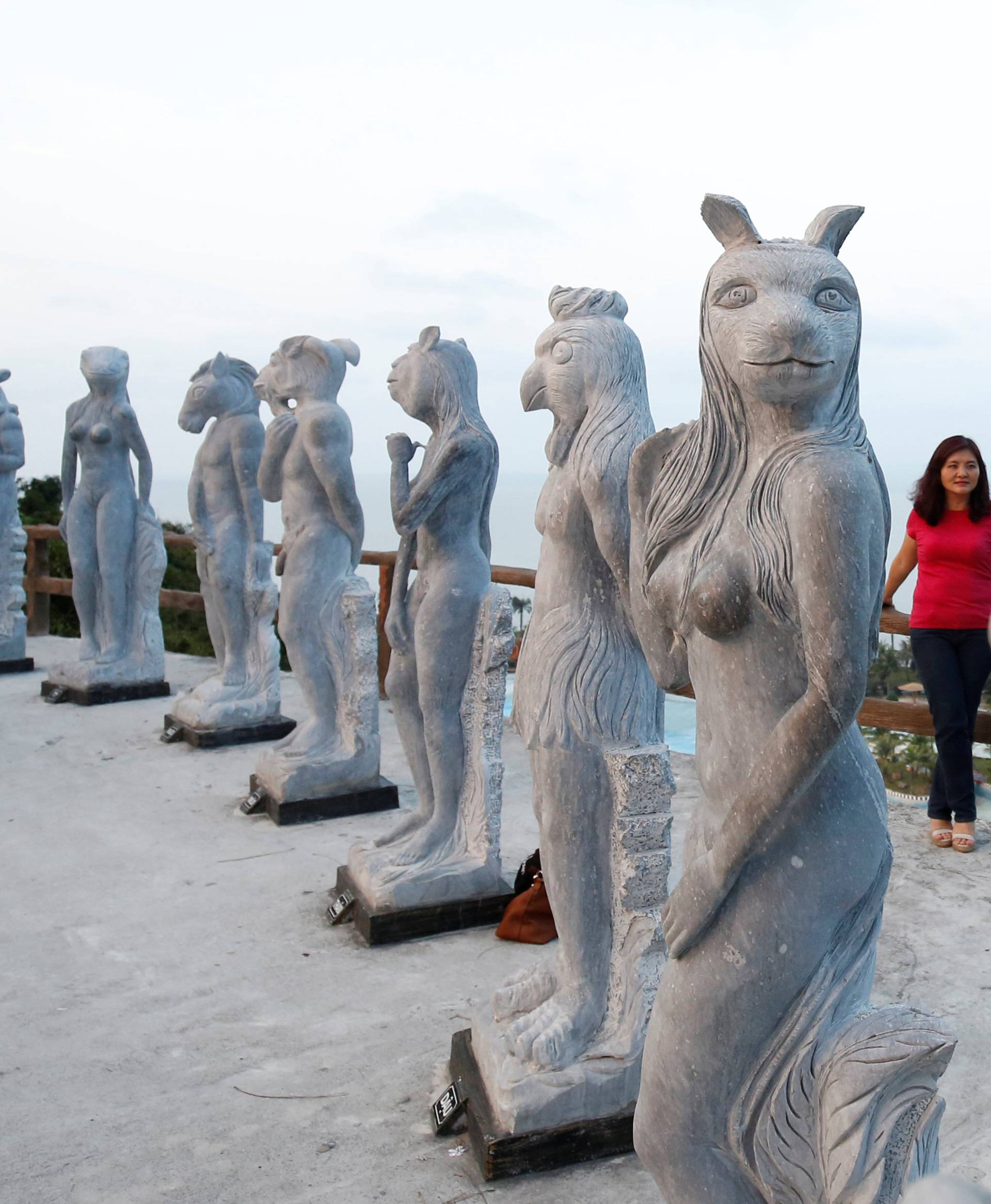 A woman stands near godlike sculptures with animal heads and human genitalia at Hon Dau resort in Hai Phong city, east of Hanoi