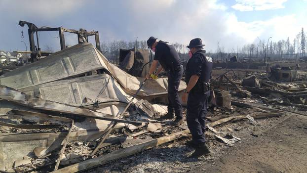 Two RCMP officers survey damage from the large wildfire that is burning in and around Ft McMurray, Alberta, Canada
