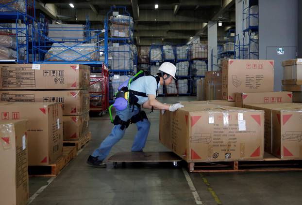 Okutani, 57, a contract worker of Ueda Co., Ltd., wears an Atoun Inc. Power Assist Suit, as he works at a distribution center in Kawasaki