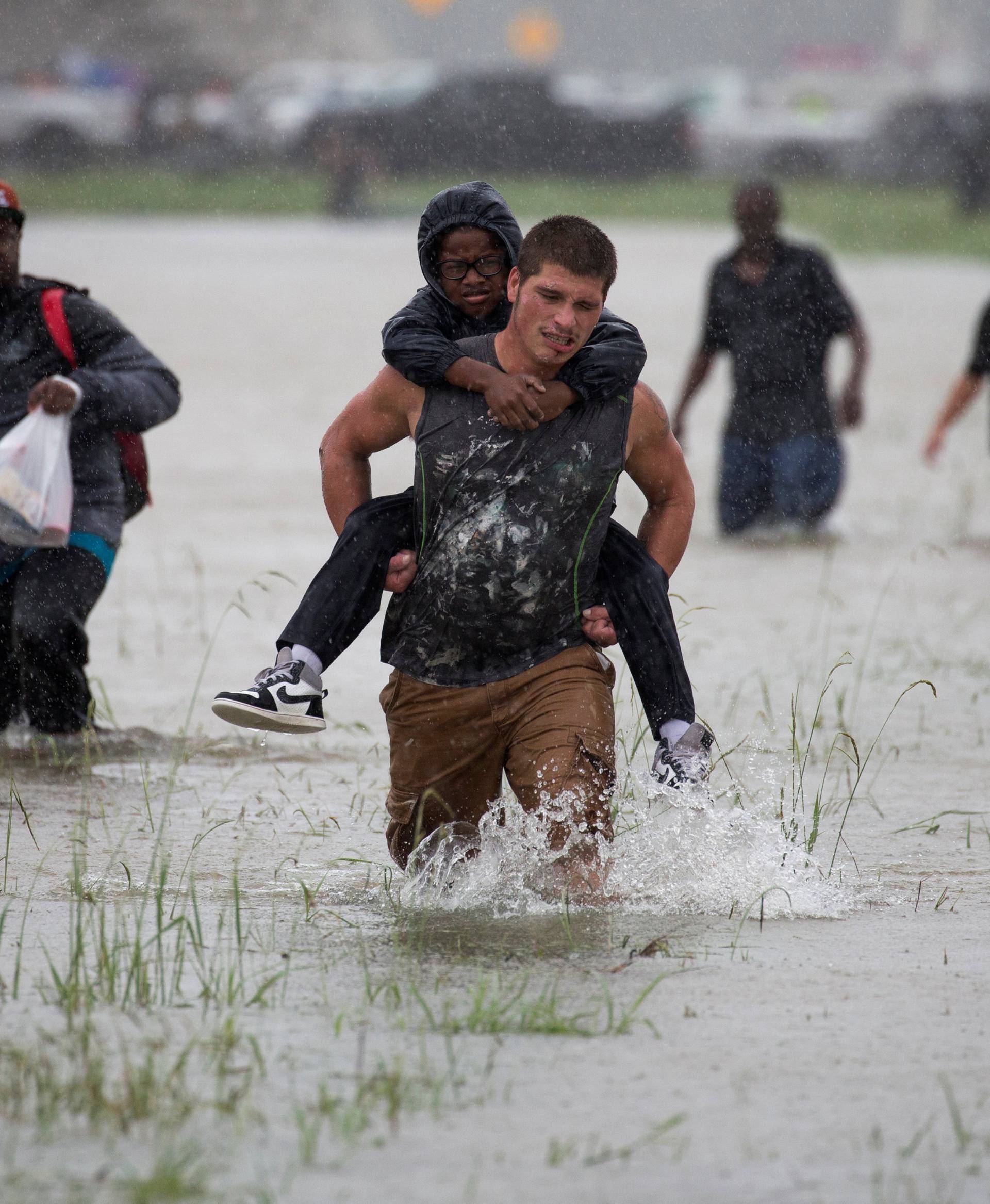 A man wades through flood waters from Tropical Storm Harvey while helping evacuate a boy in east Houston, Texas