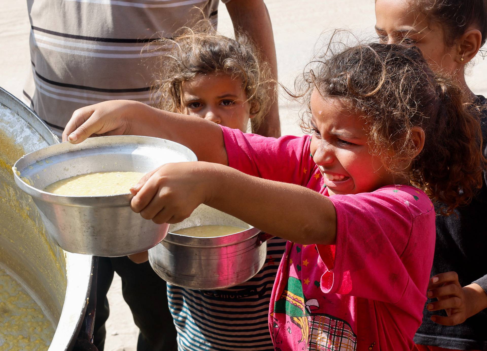 Palestinians gather to receive food cooked by a charity kitchen, in Khan Younis