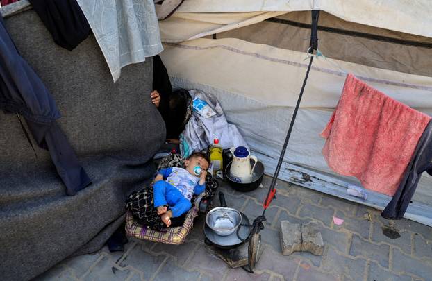 A displaced Palestinian child lies in a seat at an UNRWA school, in Khan Younis, in the southern Gaza Strip