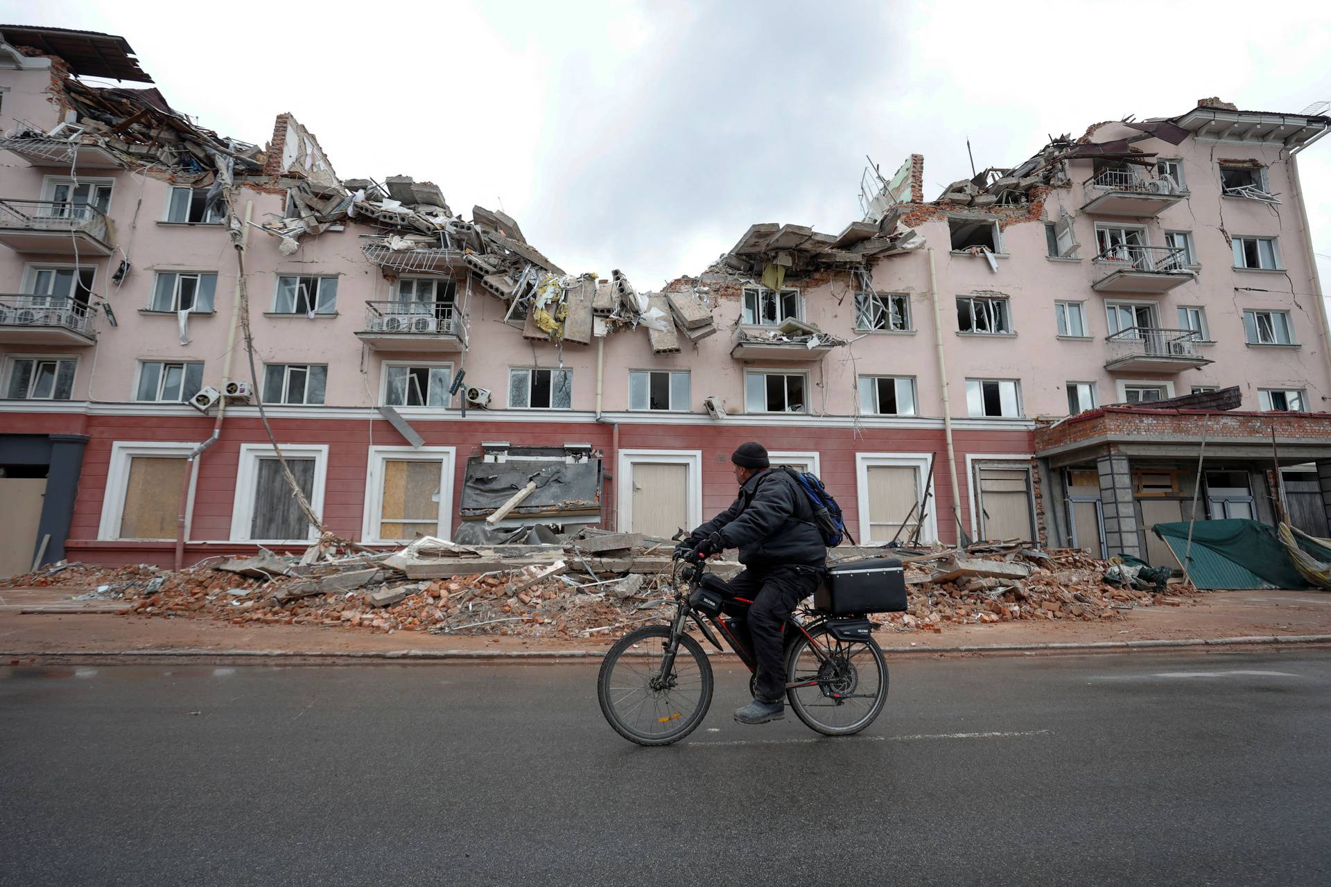 A local man rides a bicycle past the hotel Ukraina (Ukraine) destroyed by an airstrike in Chernihiv