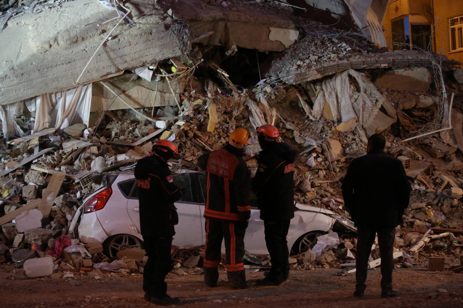 Rescue workers look at a collapsed building after an earthquake in Elazig