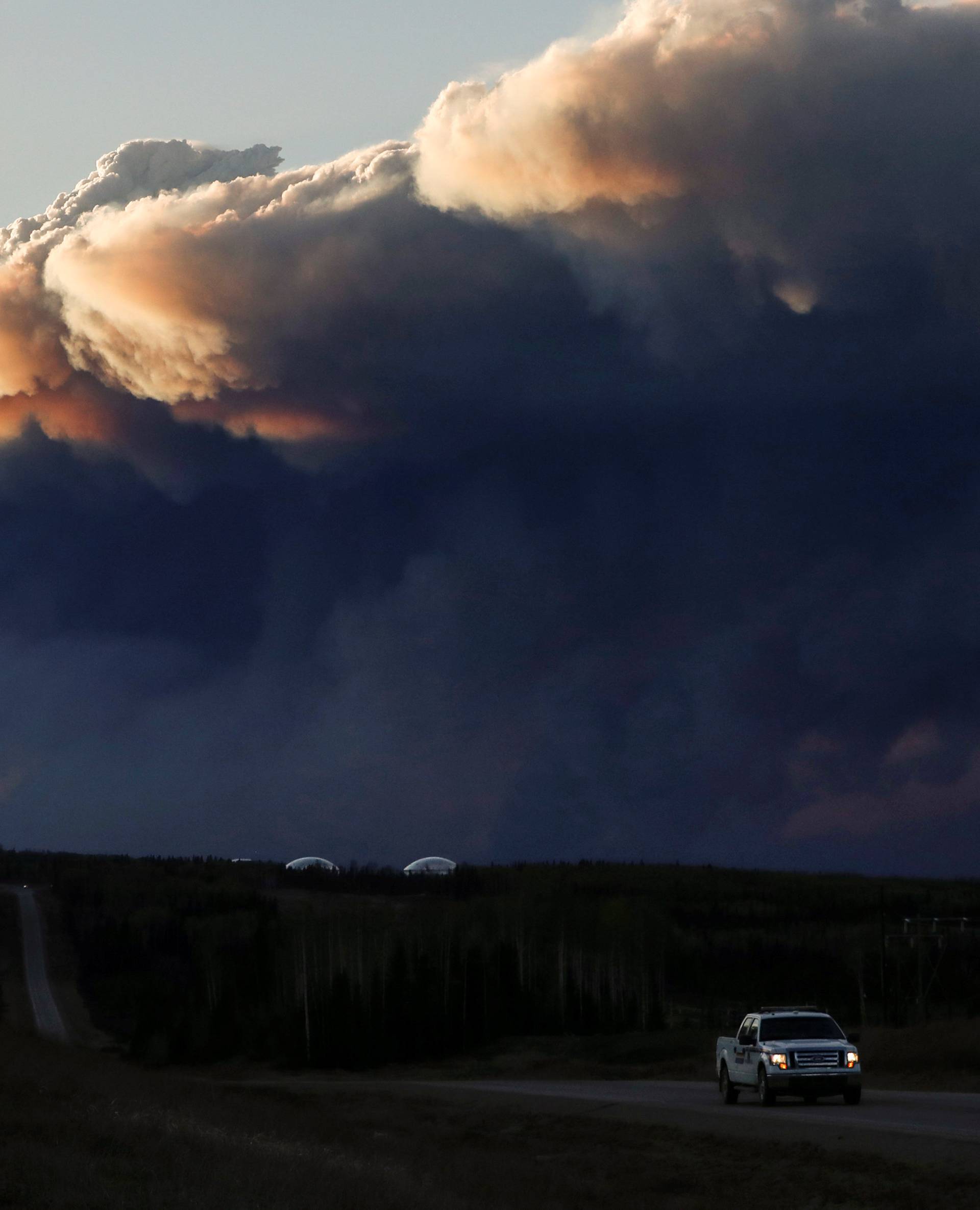 Smoke billows from the Fort McMurray wildfires as a truck drives down the highway in Kinosis
