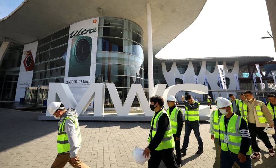 Workers walk past a giant MWC logo ahead of the Mobile World Congress at Fira de Barcelona