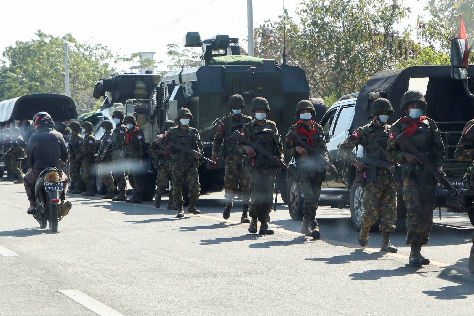 Soldiers walk as others stand guard next to armored vehicles in Naypyitaw