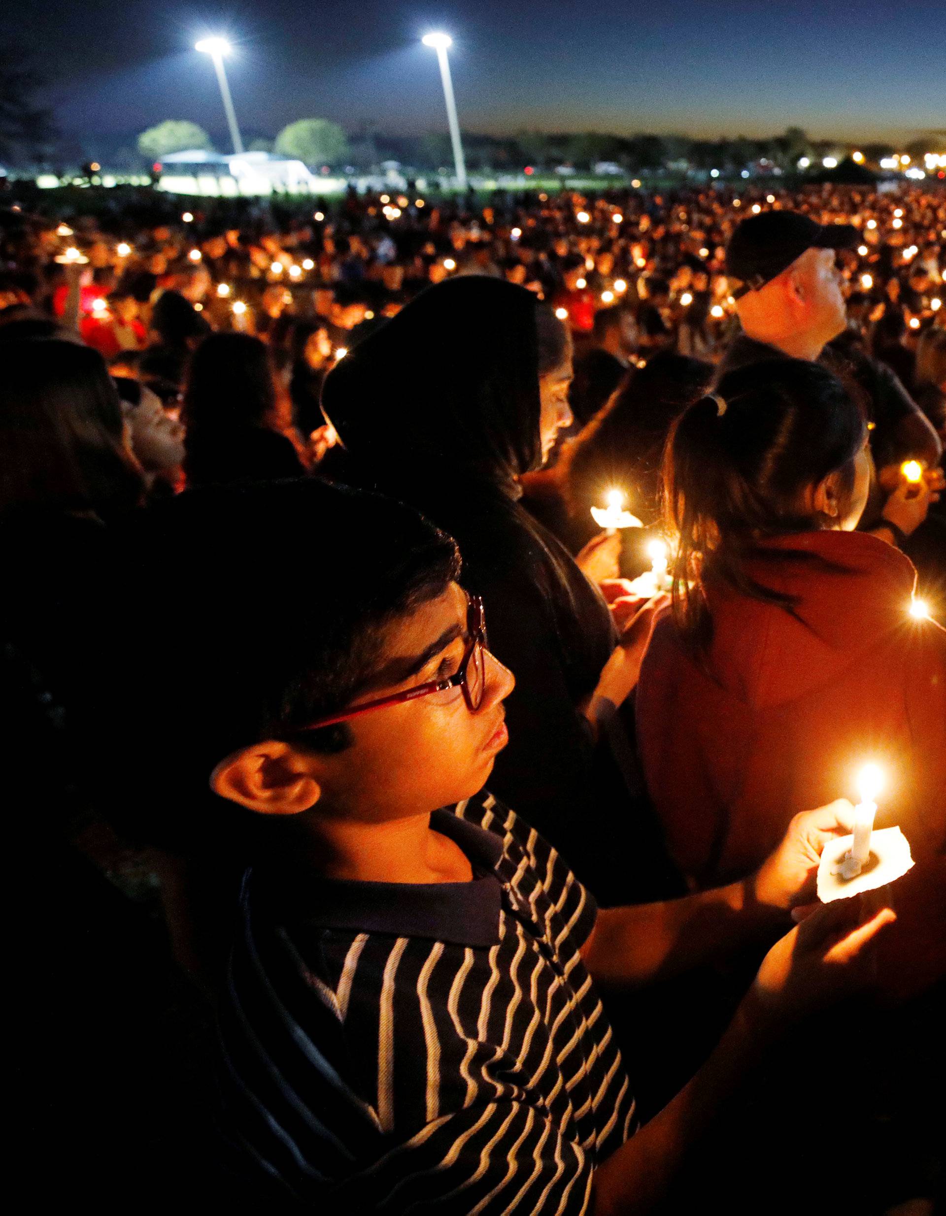 People attend a candlelight vigil the day after a shooting at Marjory Stoneman Douglas High School in Parkland