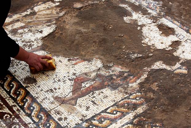 An Israel Antiquities Authority worker cleans a mosaic floor decorated with a figure, which archaeologists say is 1,800 years old and was unearthed during an excavation in Caesarea